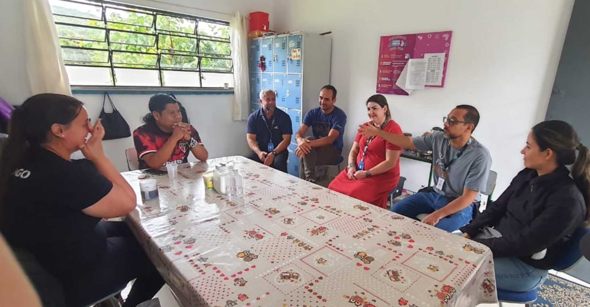 Representantes do Senac reunidos ao redor de uma mesa com o cacique da aldeia
